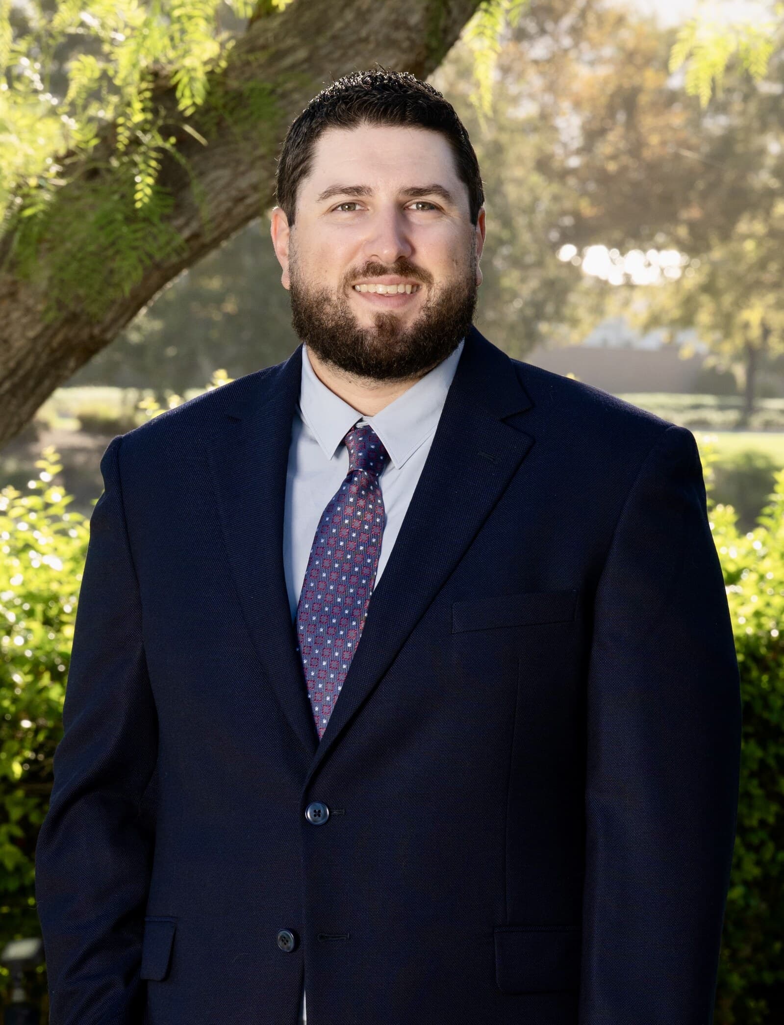 Frank Sandoval standing outdoors in a navy suit